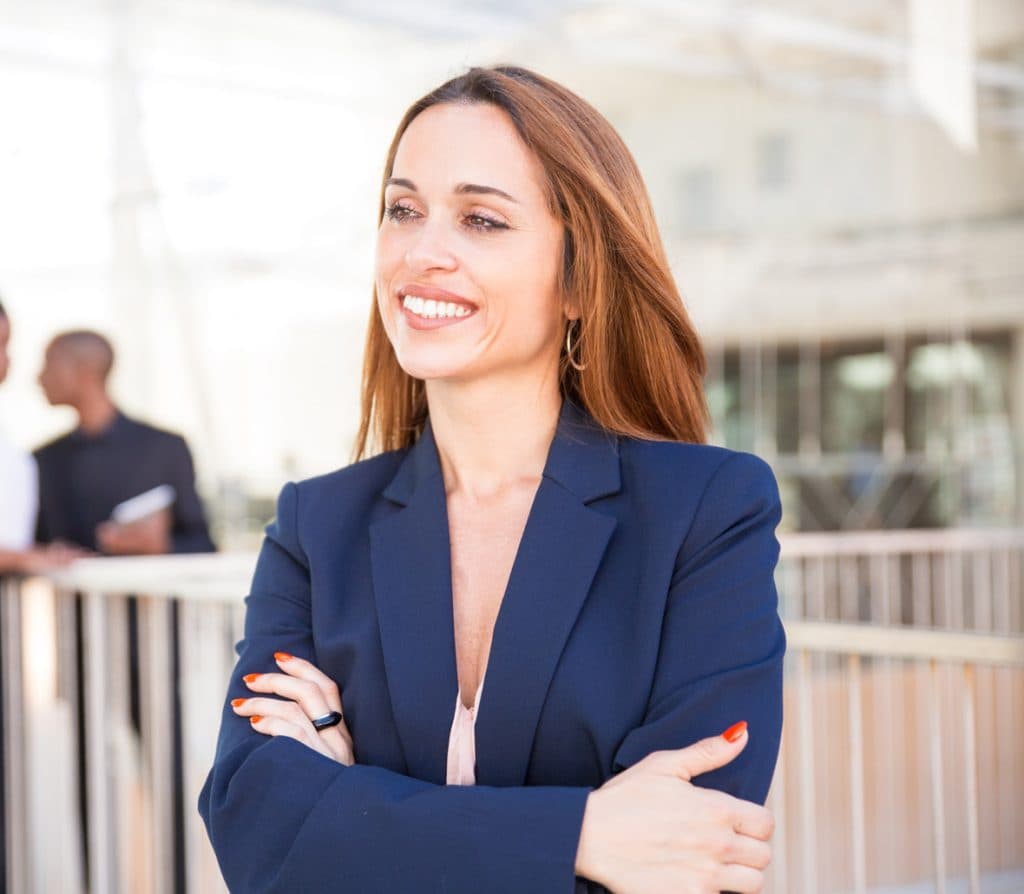 Uma mulher de negócios com os braços cruzados na frente de um grupo de pessoas.