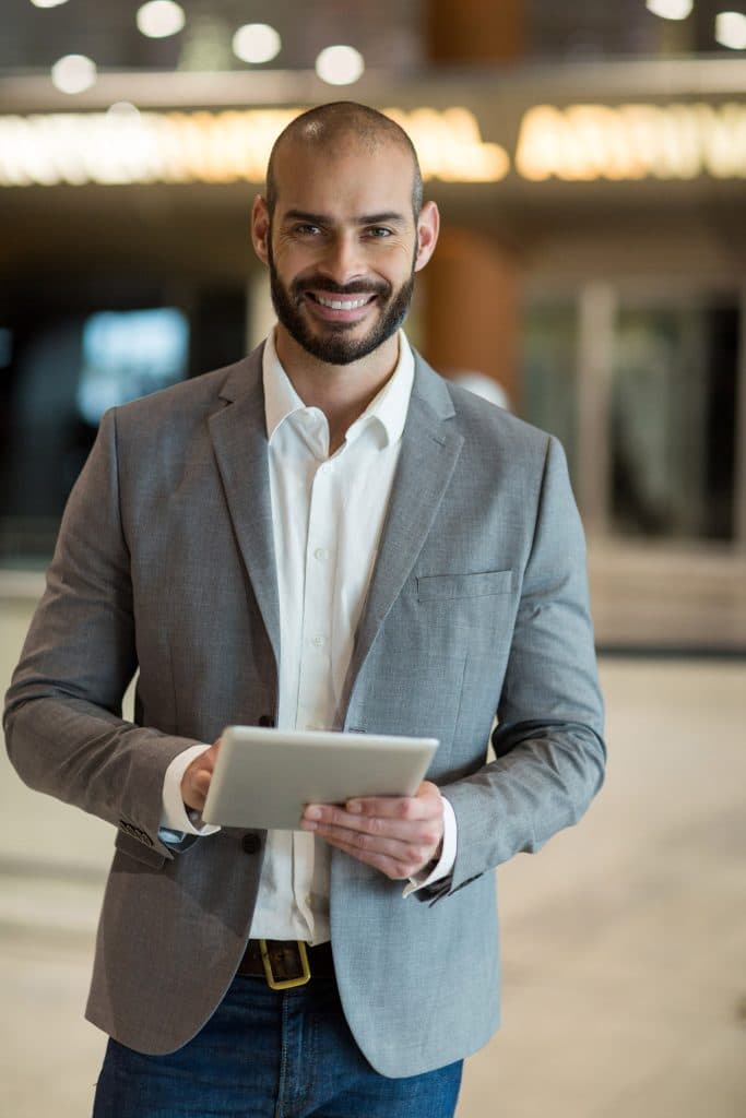 A businessman holding a tablet in an airport.