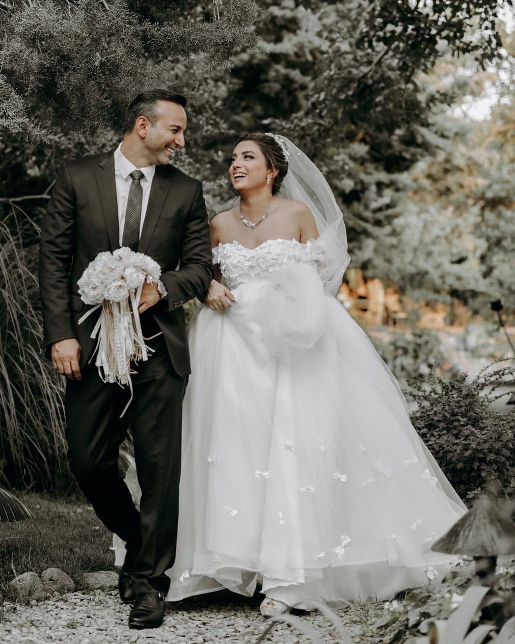 A bride and groom walking through a garden.