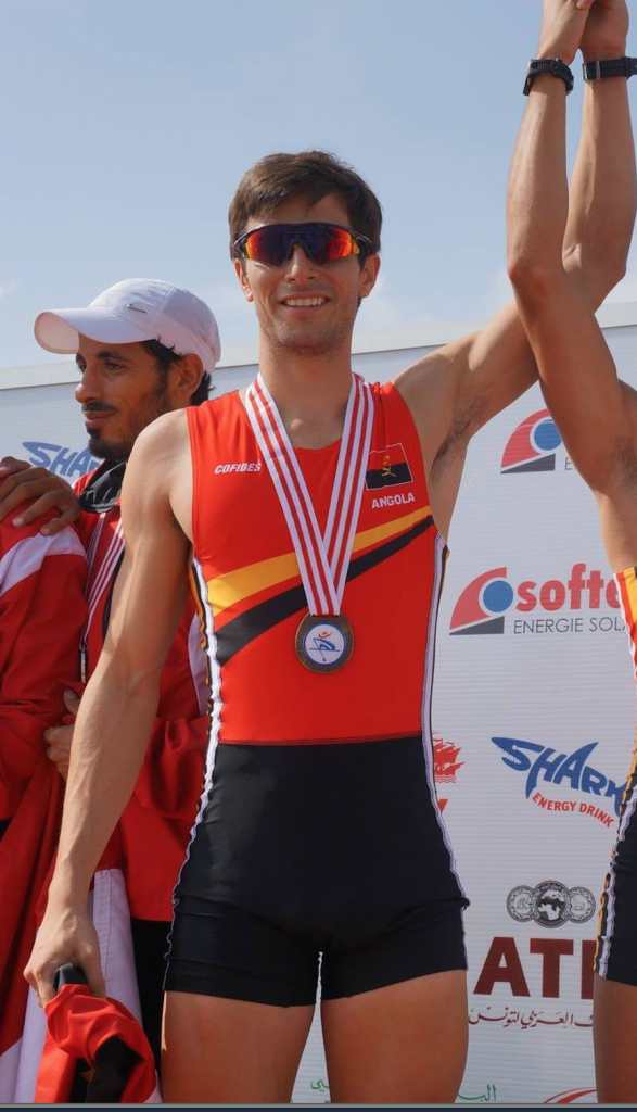 Dois homens segurando suas medalhas em um pódio.