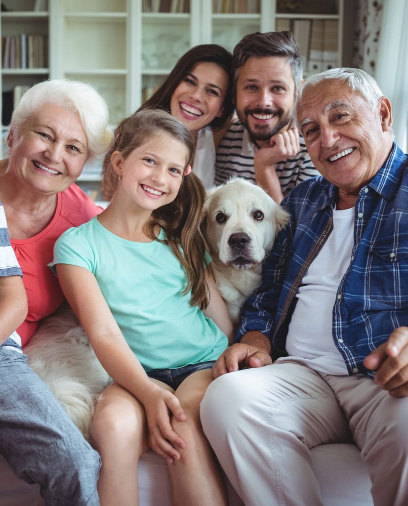 Uma família sentada em um sofá com um cachorro.