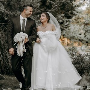 A bride and groom walking through a garden.